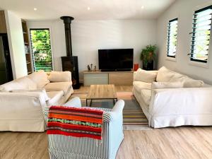 a living room with white furniture and a flat screen tv at Stunning Yamba Beach House! 3B+ in Yamba