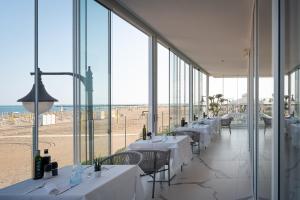 un restaurant avec des tables et des chaises ainsi qu'une plage dans l'établissement Unico Hotel Caorle, à Caorle