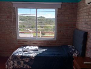 ein Schlafzimmer mit einem Bett und einem großen Fenster in der Unterkunft Terrazas de mayu in Villa Icho Cruz