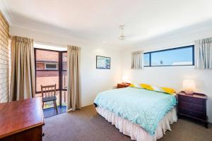 a bedroom with a bed and a desk and window at Location+ Ocean & headland views. Wifi, linen + in Yamba