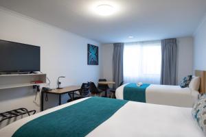 a hotel room with two beds and a flat screen tv at Bairnsdale International in Bairnsdale