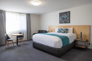 a hotel room with a bed and a table and chairs at Bairnsdale International in Bairnsdale