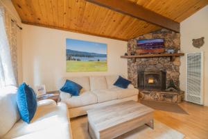 sala de estar con sofá y chimenea de piedra en Sherwood Cottage - Charming and cozy cabin that has back deck with a Hot Tub!, en Big Bear City