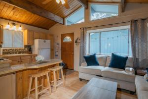 Una sala de estar con un sofá y una cocina. en Sherwood Cottage - Charming and cozy cabin that has back deck with a Hot Tub!, en Big Bear City