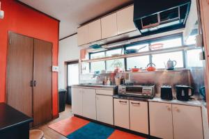 a kitchen with red walls and white cabinets at SLOW HOUSE kesennuma - Vacation STAY 31901v in Kesennuma