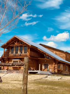 ein Blockhaus mit einem Zaun davor in der Unterkunft Sportsman Lodge Melrose MT in Melrose