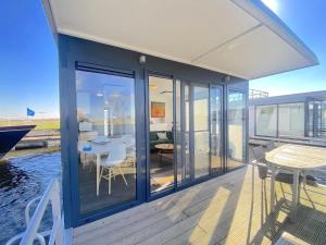 a house with a deck with a table and chairs at Woonboot Bertan in Nieuwpoort
