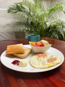a plate of breakfast food with toast and a bowl of fruit at Santuario Getsemani Hostel in Cartagena de Indias