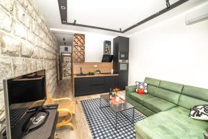 a living room with a green couch and a stone wall at Apartman Roccia in Trebinje