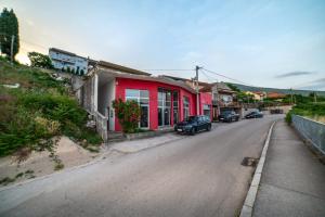 a street with a red house and cars parked on the road at Apartman Roccia in Trebinje
