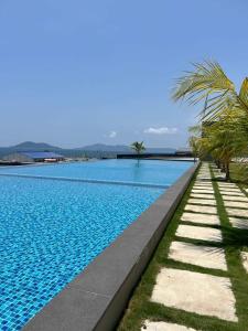 a large swimming pool with palm trees next to it at Lovely Seaview Condo TII @ Jesselton Quay in Kota Kinabalu