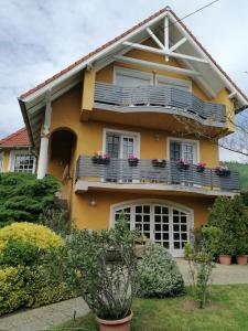 una casa amarilla con un balcón con flores. en Vár-Lak Resort en Balatonederics