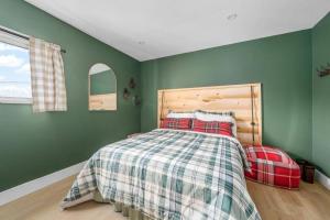 a bedroom with green walls and a bed with a plaid blanket at Urban Cabin - Downtown Picton in Picton