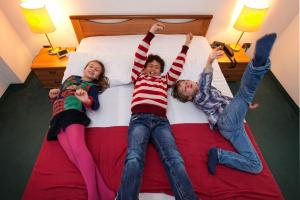 three children laying on a bed with their arms in the air at Hotel Kappa in Mestre