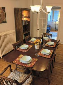 uma sala de jantar com mesa e cadeiras com pratos e copos em Historic Oakpark Home 