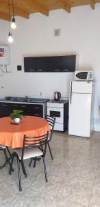 eine Küche mit einem Tisch und einem weißen Kühlschrank in der Unterkunft Posada Atardeceres in Puan