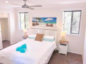 a bedroom with a white bed and two windows at DELUXE Escape! Central, NEW & Spacious 3 Bed in Yamba
