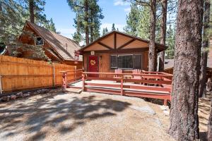 una cabaña con un banco delante de una valla en Ponderosa Hill Cabin - Perfect cozy escape! Located in a prime area for a family getaway!, en Big Bear City