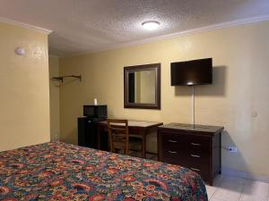 Habitación de hotel con cama, escritorio y TV. en Kings Rest Motel, en Lemoore