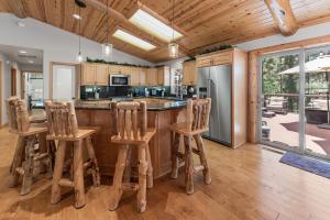 a kitchen with wooden cabinets and a bar with stools at Paradise Peak - One of kind and breathtaking log cabin with Hot Tub and Game Room! in Big Bear Lake
