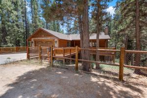 a log cabin in the woods with a fence at Paradise Peak - One of kind and breathtaking log cabin with Hot Tub and Game Room! in Big Bear Lake