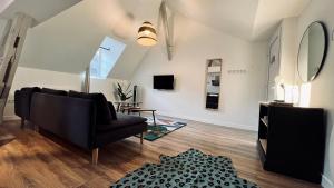 a living room with a black couch and a mirror at RhizHome - Coeur de ville, appartement spacieux in Auxerre