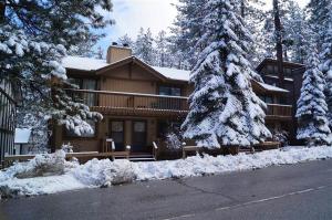 a large house with snow covered trees in front of it at Summit Getaway Condo - Affordable and ideally located, Wood burning fireplace! Walk to Ski Resort in Big Bear Lake