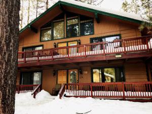 een groot houten huis met een terras in de sneeuw bij Summit Escape B - Rustic cabin with a hot tub and barbecue! Wood fireplace! Walk to Slopes! in Big Bear Lake