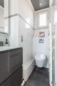 a white bathroom with a toilet and a sink at Auteuil Cozy Studio in Paris