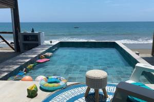 una piscina junto a una playa con el océano en La Soñadora casa frente al mar con piscina, en Canoas