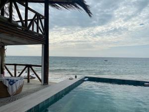 una piscina junto a una playa con el océano en La Soñadora casa frente al mar con piscina en Canoas