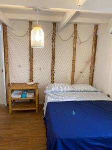 Un dormitorio con una cama azul y una mesa en La Soñadora casa frente al mar con piscina en Canoas
