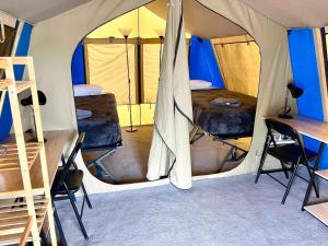 a tent with two beds and a desk in it at Mycow Accommodation Mackay in Mackay