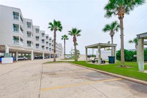 a parking lot in front of a building with palm trees at A Slice of Seawall in Galveston