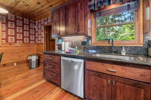 uma cozinha com armários de madeira, um lavatório e uma janela em Stillwater Cove Lakefront - Breathtaking views, charming vintage cabin, woodsy interior! Boat Dock! em Big Bear Lake