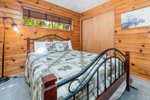 um quarto com uma cama num quarto com paredes de madeira em Stillwater Cove Lakefront - Breathtaking views, charming vintage cabin, woodsy interior! Boat Dock! em Big Bear Lake