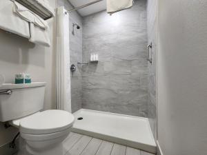 a white bathroom with a toilet and a shower at The Grove at Pismo Beach in Pismo Beach