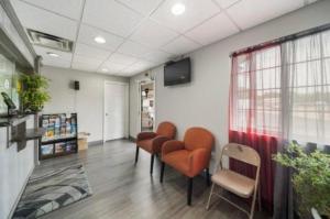 una sala de espera con sillas naranjas y una ventana en Deluxe Inn Miami OK, en Miami