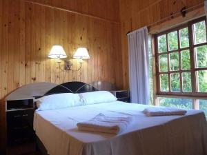 een slaapkamer met een groot bed en 2 handdoeken bij Hotel Los Lapachos in Puerto Iguazú