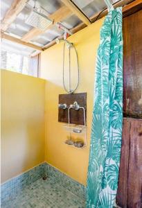 y baño con ducha y paredes de color amarillo. en Luminosa Uvita Hostel, en Uvita