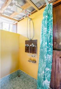 a bathroom with a shower with yellow walls at Luminosa Uvita Hostel in Uvita
