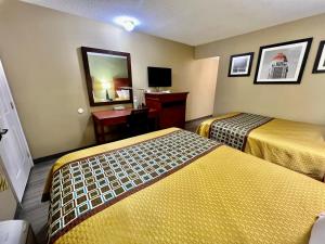 Cette chambre comprend deux lits, un bureau et un miroir. dans l'établissement Deluxe Inn Miami OK, à Miami
