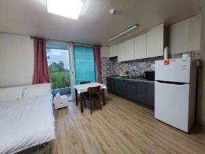 済州市にあるSky Oreum Pensionのキッチン(白い冷蔵庫、テーブル付)
