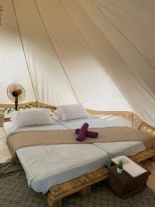 2 Betten in einem Zelt mit einem lila ausgestopften Tier in der Unterkunft Sailor's Rest in Janda Baik