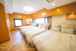 three beds in a room with wooden walls and wood floors at la3 hotel 新宿三階建て一軒家（屋内エレベーター付き) in Tokyo