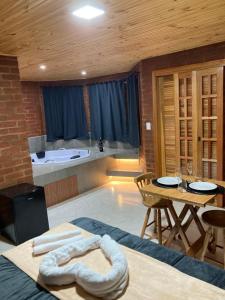 a room with a bed and a table and a kitchen at Pousada do valle in Monte Verde