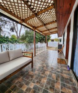 a porch with a couch and a wooden pergola at Casa en condominio cerca de la playa El Quisco Norte in El Quisco