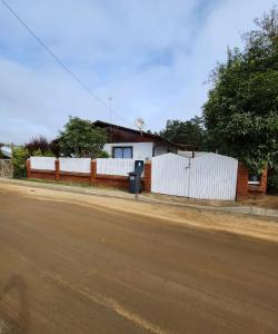 una casa con una cerca blanca al lado de una calle en Casa en condominio cerca de la playa El Quisco Norte en El Quisco