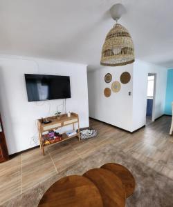a living room with a flat screen tv and a table at Casa en condominio cerca de la playa El Quisco Norte in El Quisco