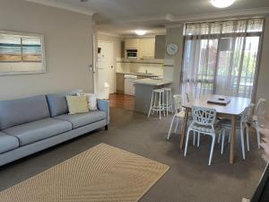 a living room with a couch and a table and chairs at The Commodore, 14, 9-11 Donald Street- Unit in the heart of town with views & free wi-fi in Nelson Bay
